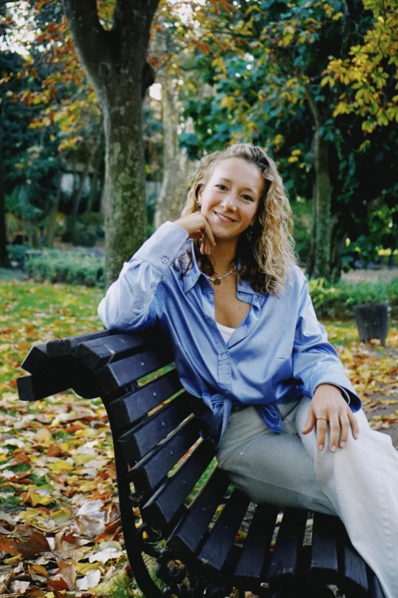 Isabel Burkhard sitting on a park bench in autumn